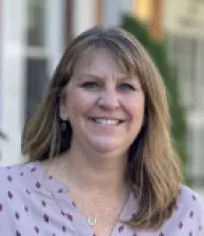 Melanie headshot. She is outside, and wearing a purple blouse. 